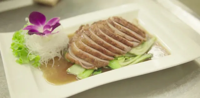 Knusprige Ente auf Pak Choi, mit Sauce und Orchideenblüte