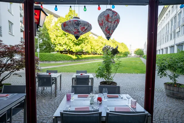Eingedeckter Tisch auf der Terrasse unter Lampions